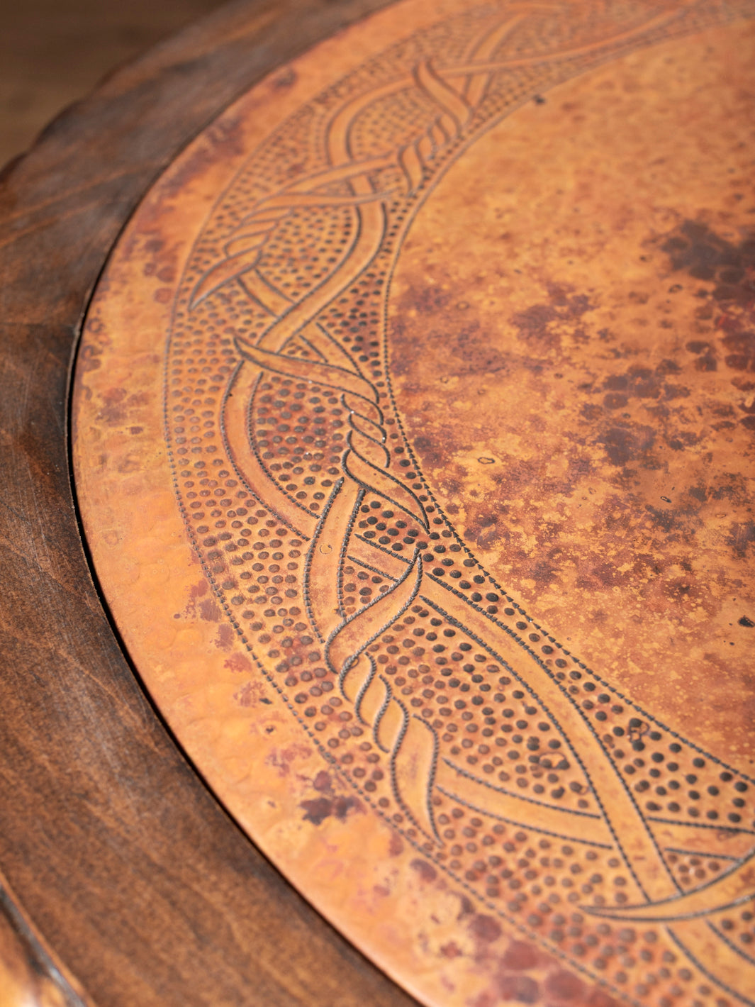 Close-up of hand-carved copper inlay design with rustic patina on western end table top