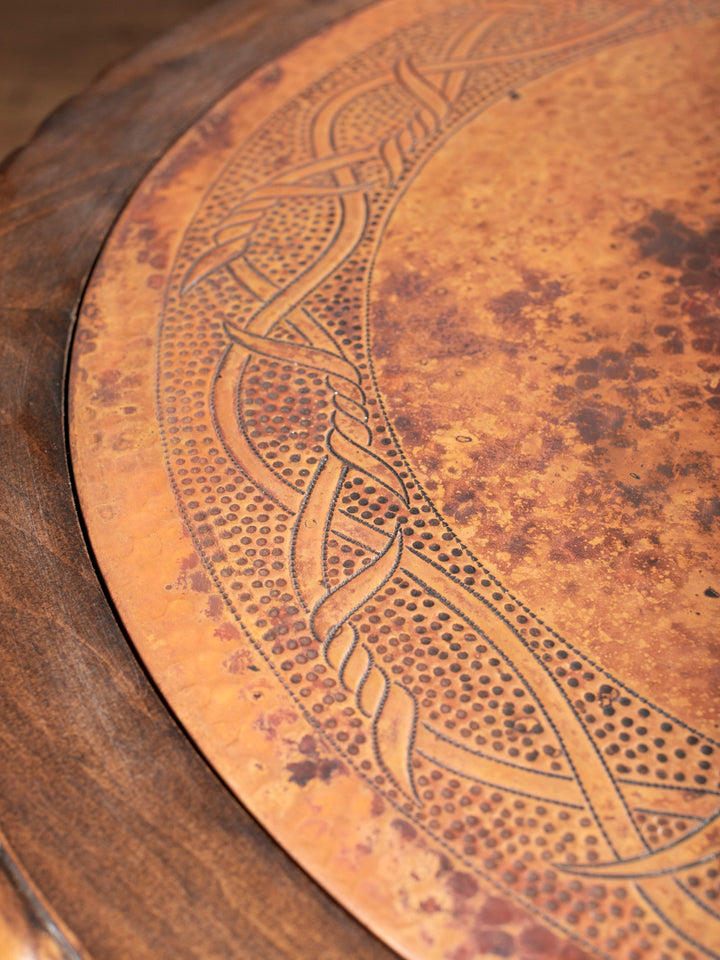 Close-up of hand-carved copper inlay design with rustic patina on western end table top
