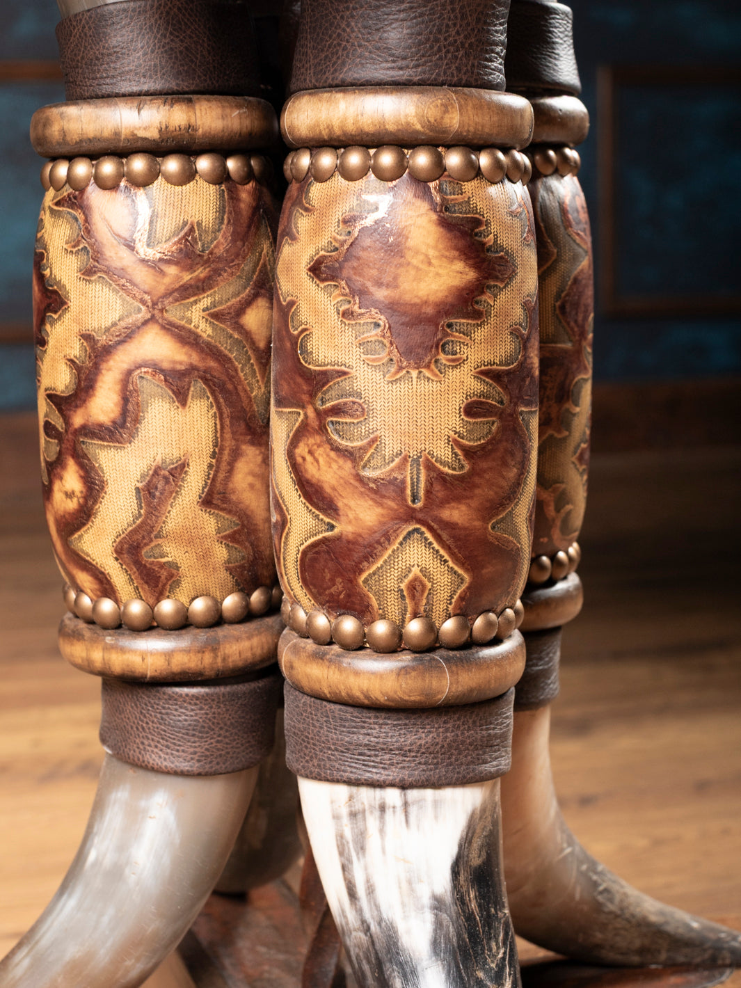 Detailed close-up of tooled leather wraps and natural steer horns supporting rustic western end table.