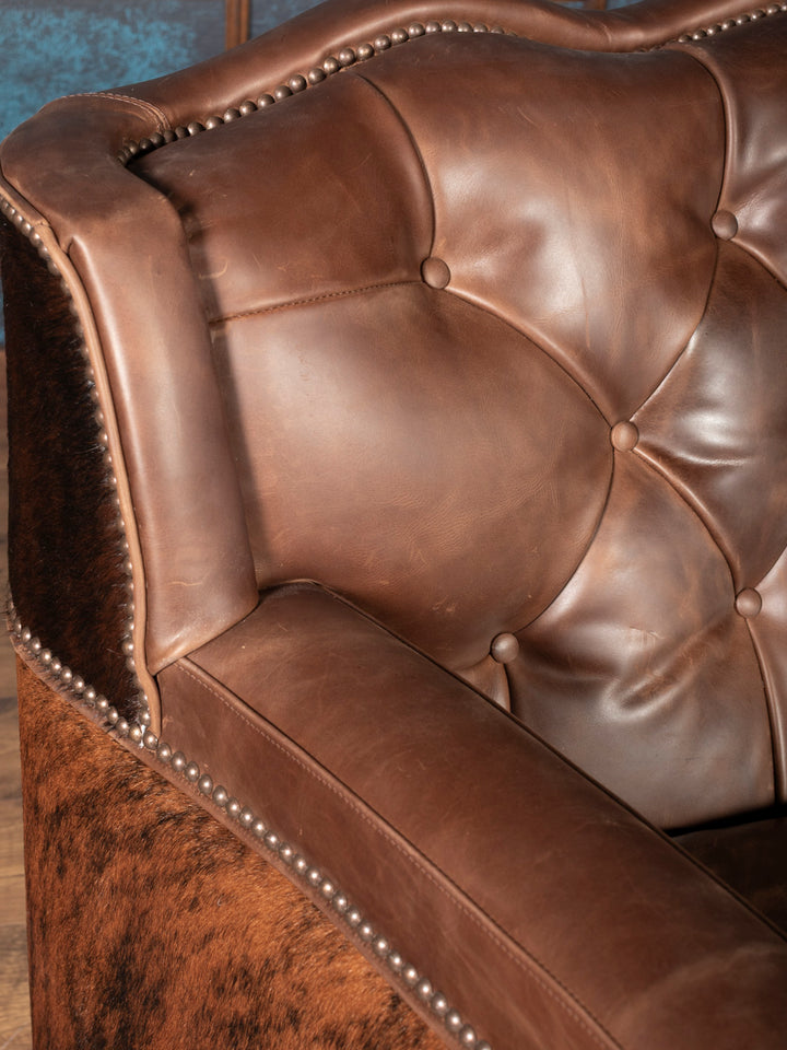 Close-up of tufting and nailhead: Tufted leather backrest with antique brass nailhead detailing