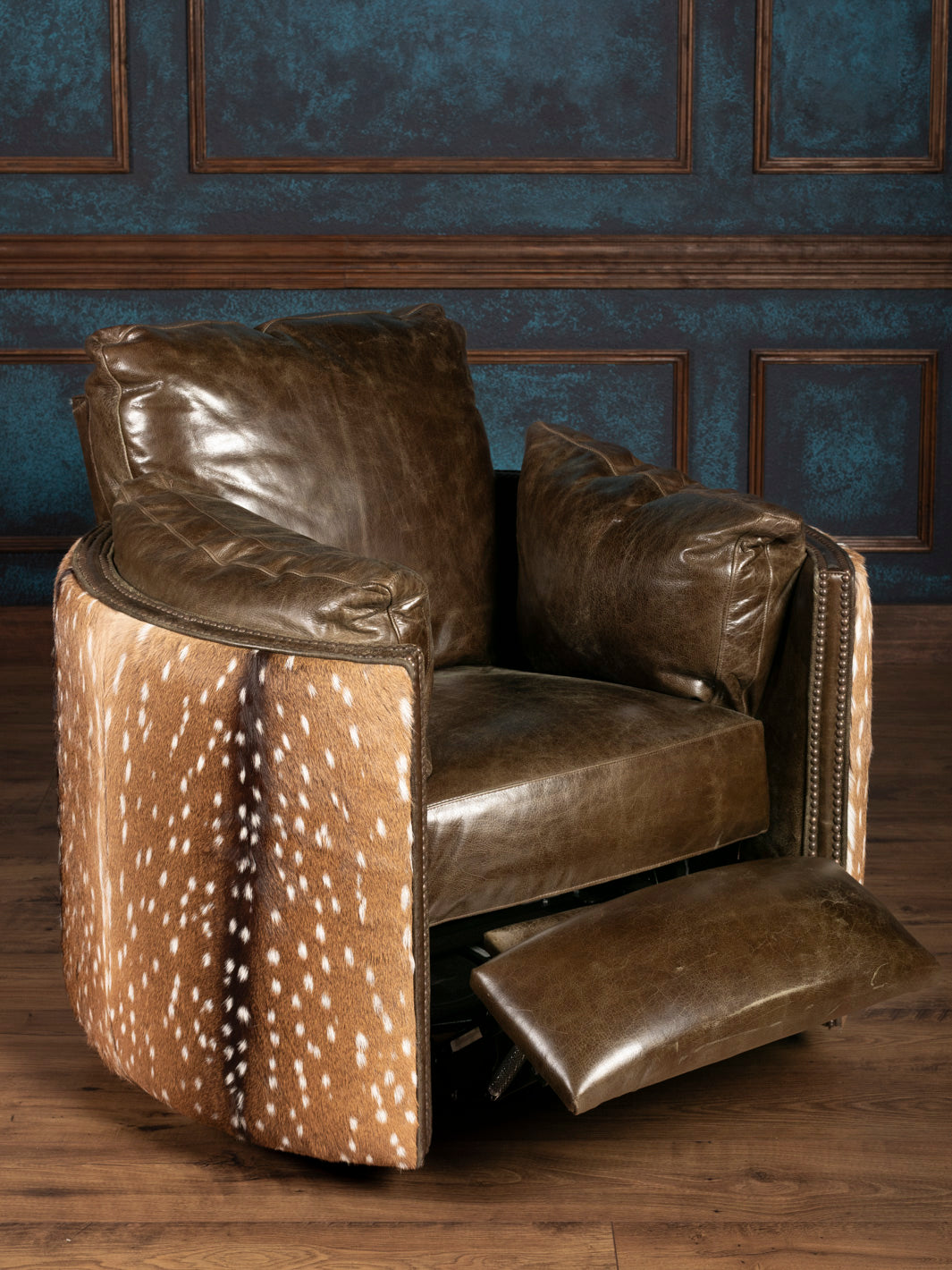 green leather armchair with deer patterned base against a blue paneled wall.