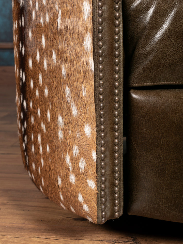 Close-up of a green leather armchair with deer hide pattern on a wooden floor.