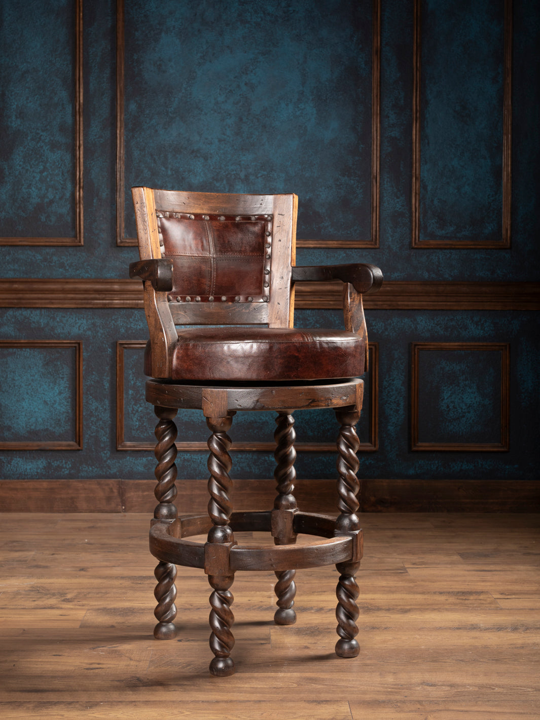brown leather bar stool with twisted wooden legs against a dark paneled wall.