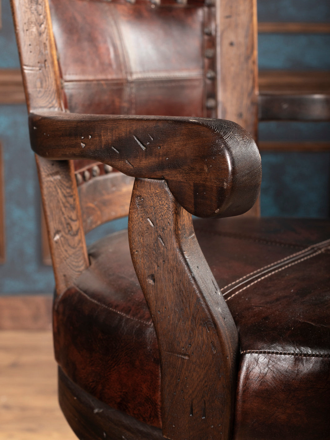 Close-up of a wooden arm with leather seat and backrest.