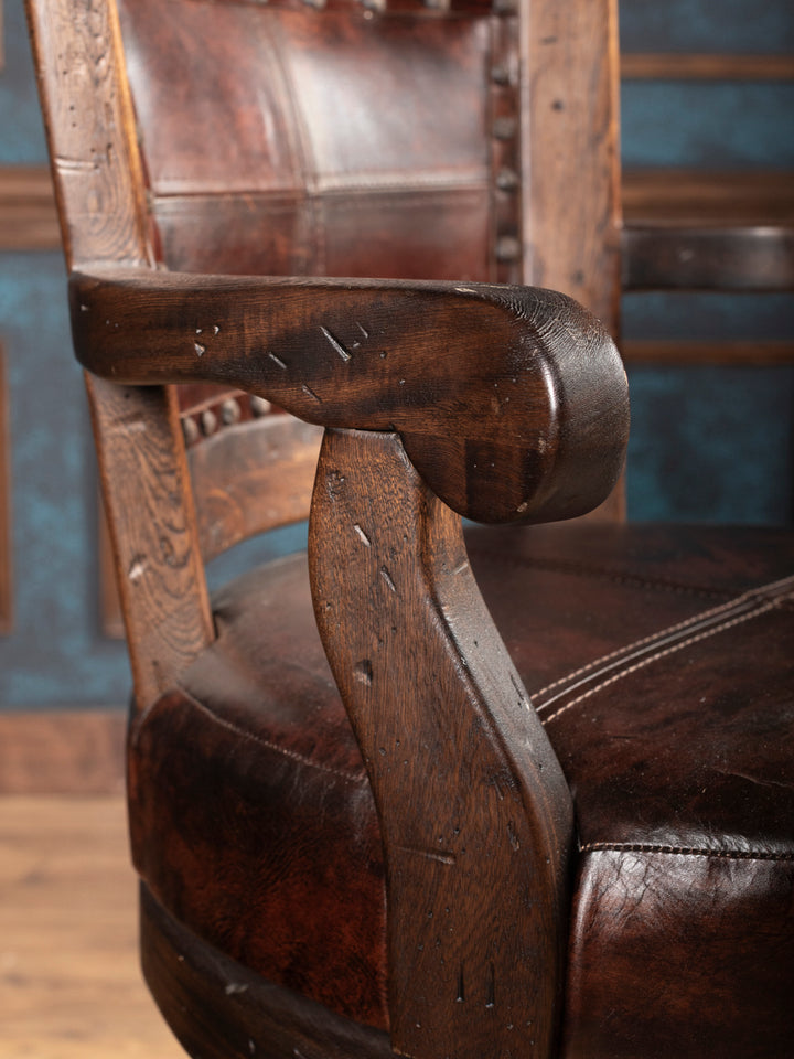 Close-up of a wooden arm with leather seat and backrest.