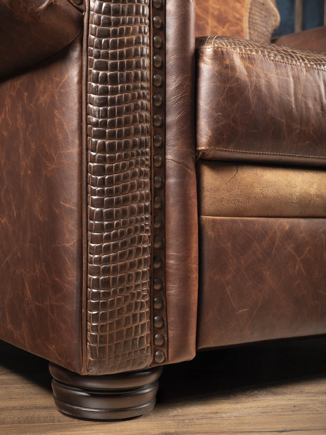 Close-up of the alligator embossed leather trim and turned wood leg on the Bison Leather Power Recliner