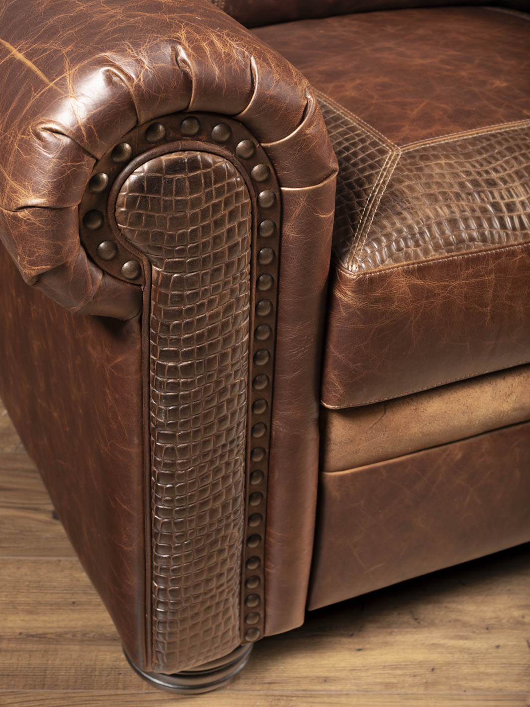 Detail of the nailhead trim and alligator embossed leather accent on the rolled arm