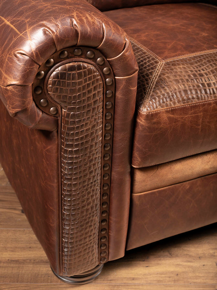 Detail of the nailhead trim and alligator embossed leather accent on the rolled arm