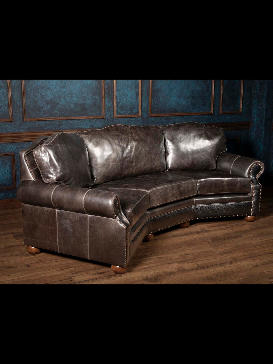 Angled view of the Brazos handcrafted Western leather sofa showcasing its curved silhouette, rolled arms, full-grain buffalo leather, and hand-tooled accents.
