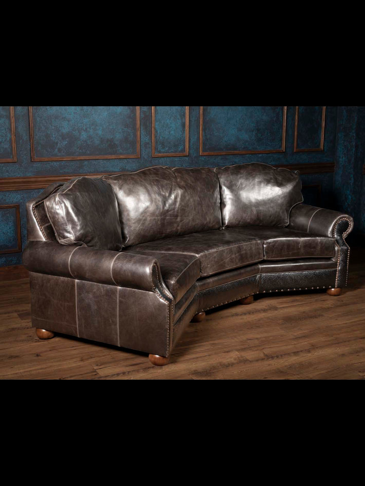 Angled view of the Brazos handcrafted Western leather sofa showcasing its curved silhouette, rolled arms, full-grain buffalo leather, and hand-tooled accents.