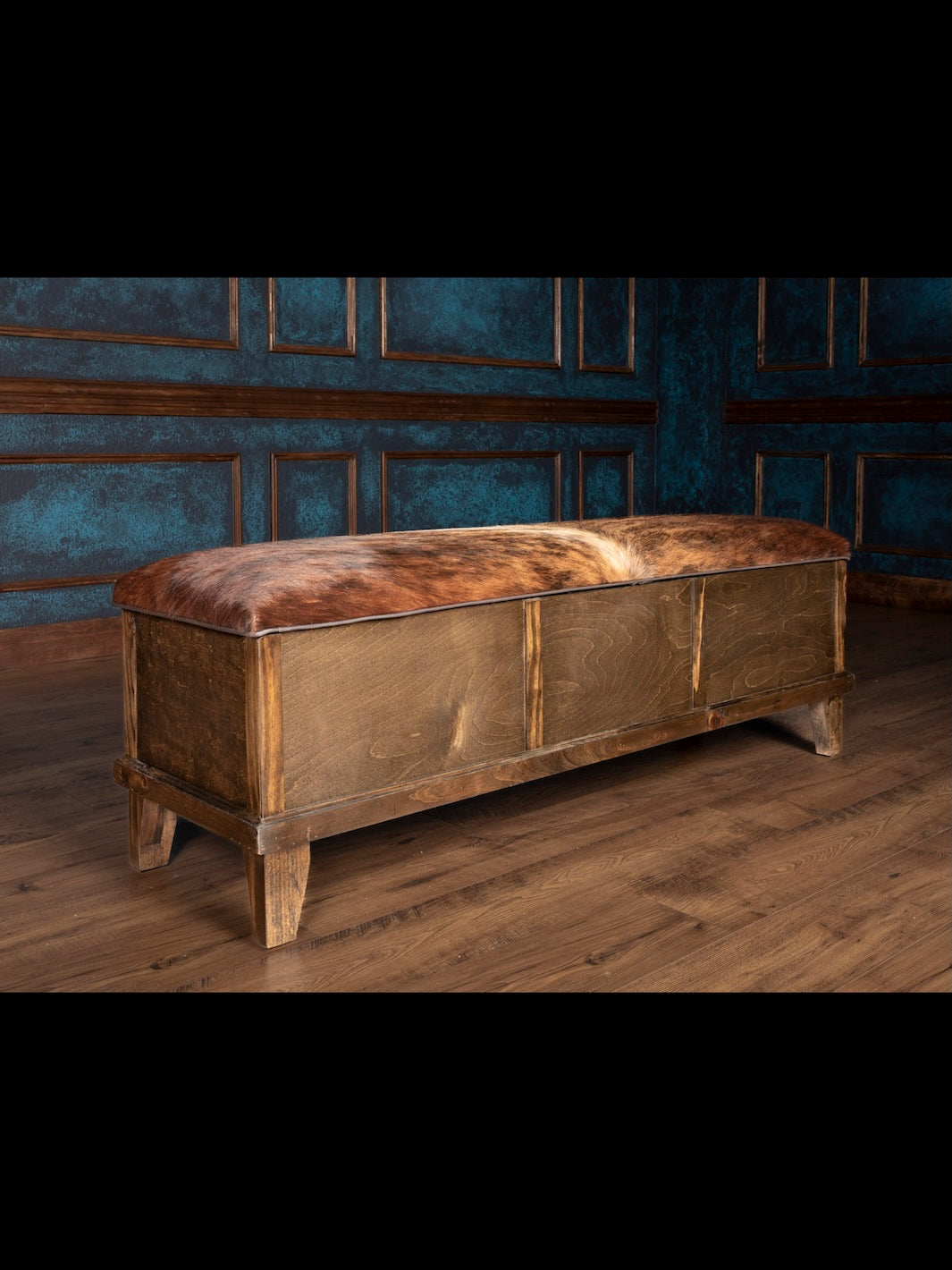 Wooden bench with leather seat in a room with blue walls and wooden floor.