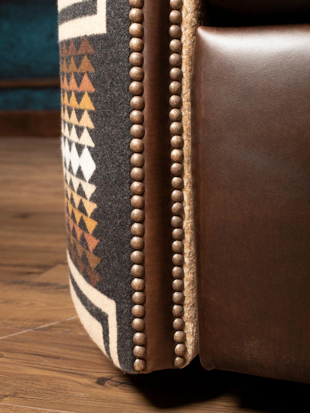 Detailed close-up view of the double contrast stitching running along the lower base panels of a hand-finished brown patina full-grain leather chair.