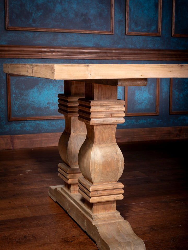 Base detail of rustic pine dining table showing hand-carved trestle support and sculpted leg profile