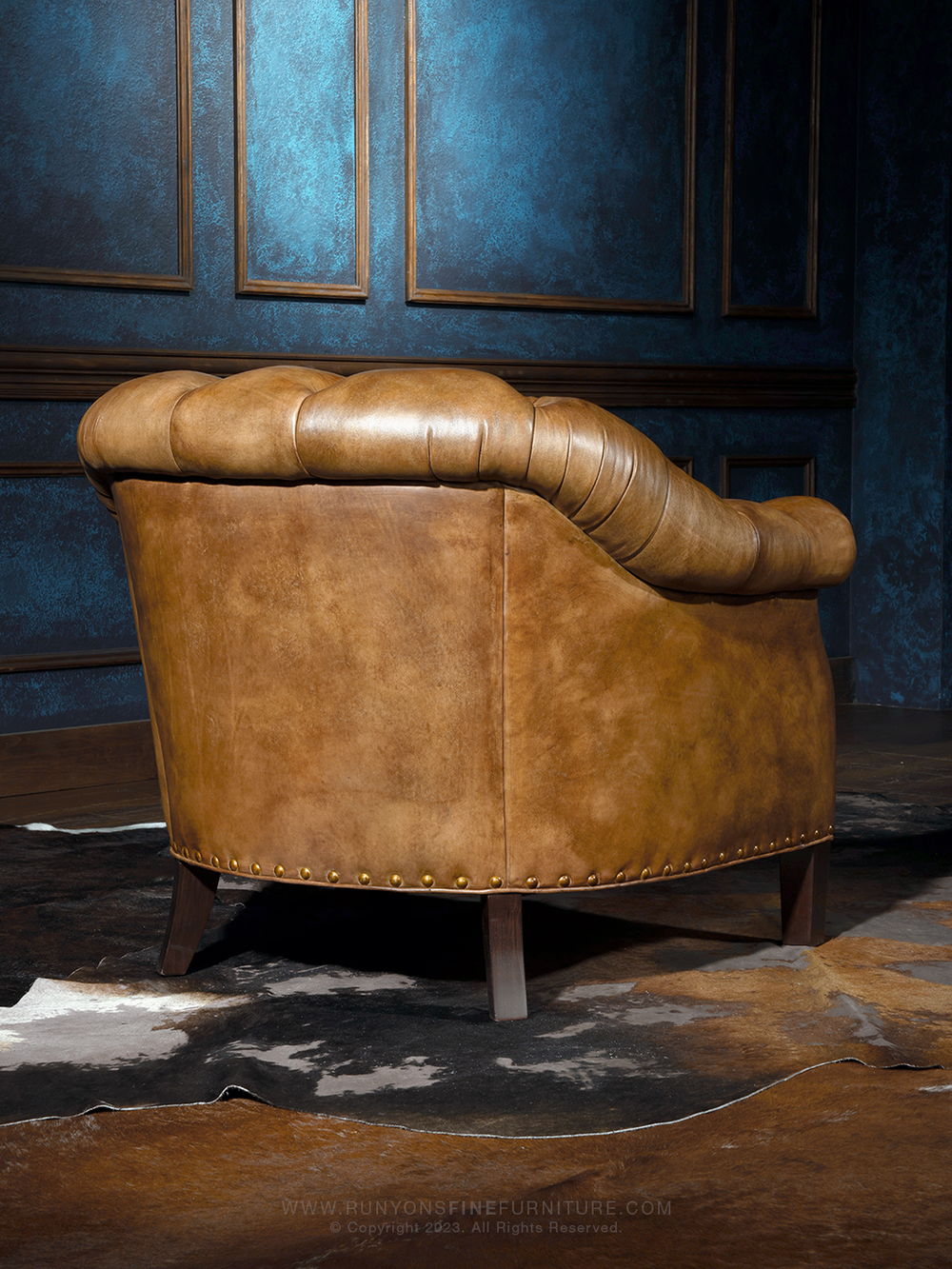 Chesterfield Leather Accent Chair in burnished brown leather with rolled arm design and tapered wooden legs in a spacious western room.
