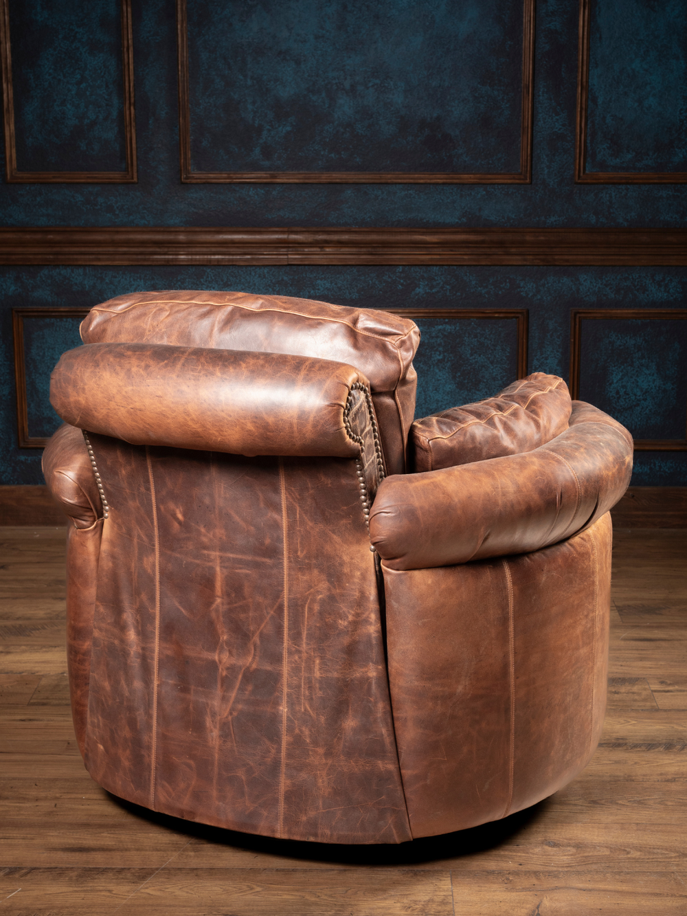 Chocolate Leather Snug Swivel Recliner with brown leather outside back and rolled arms in a western-style living space.