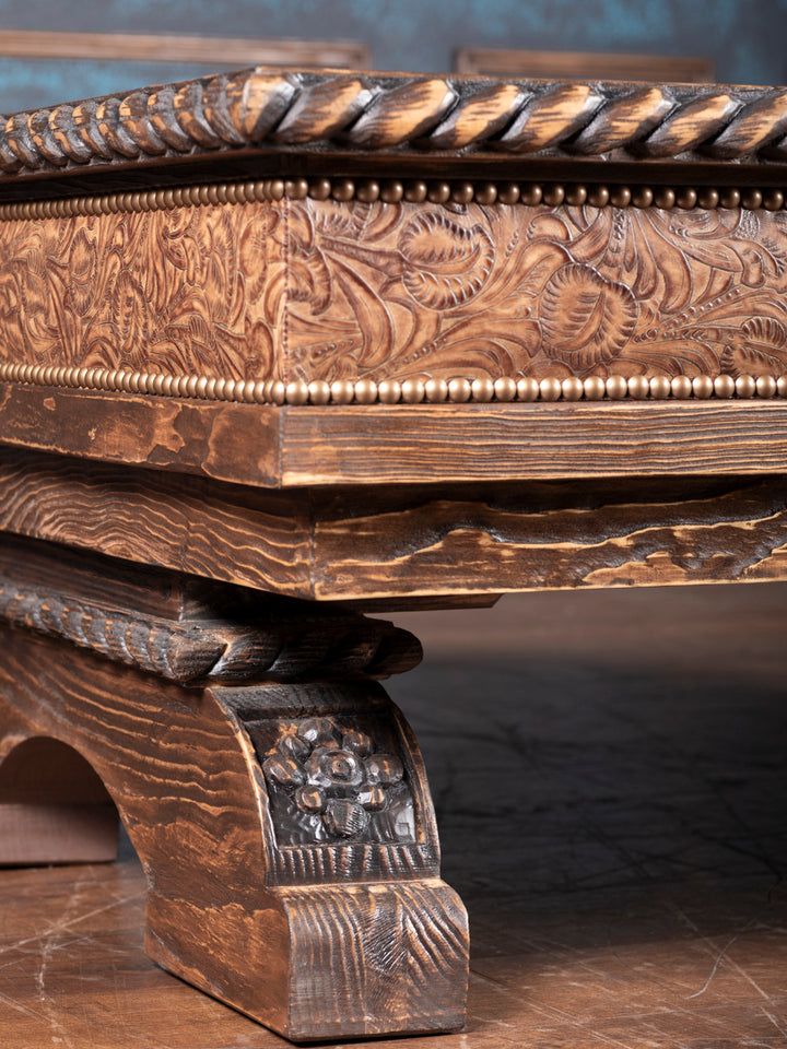 Saddle Ridge Shadow Box Coffee Table with solid wood with brown finish featuring hand-carved western detail and embossed floral leather trim in rustic living room setting.