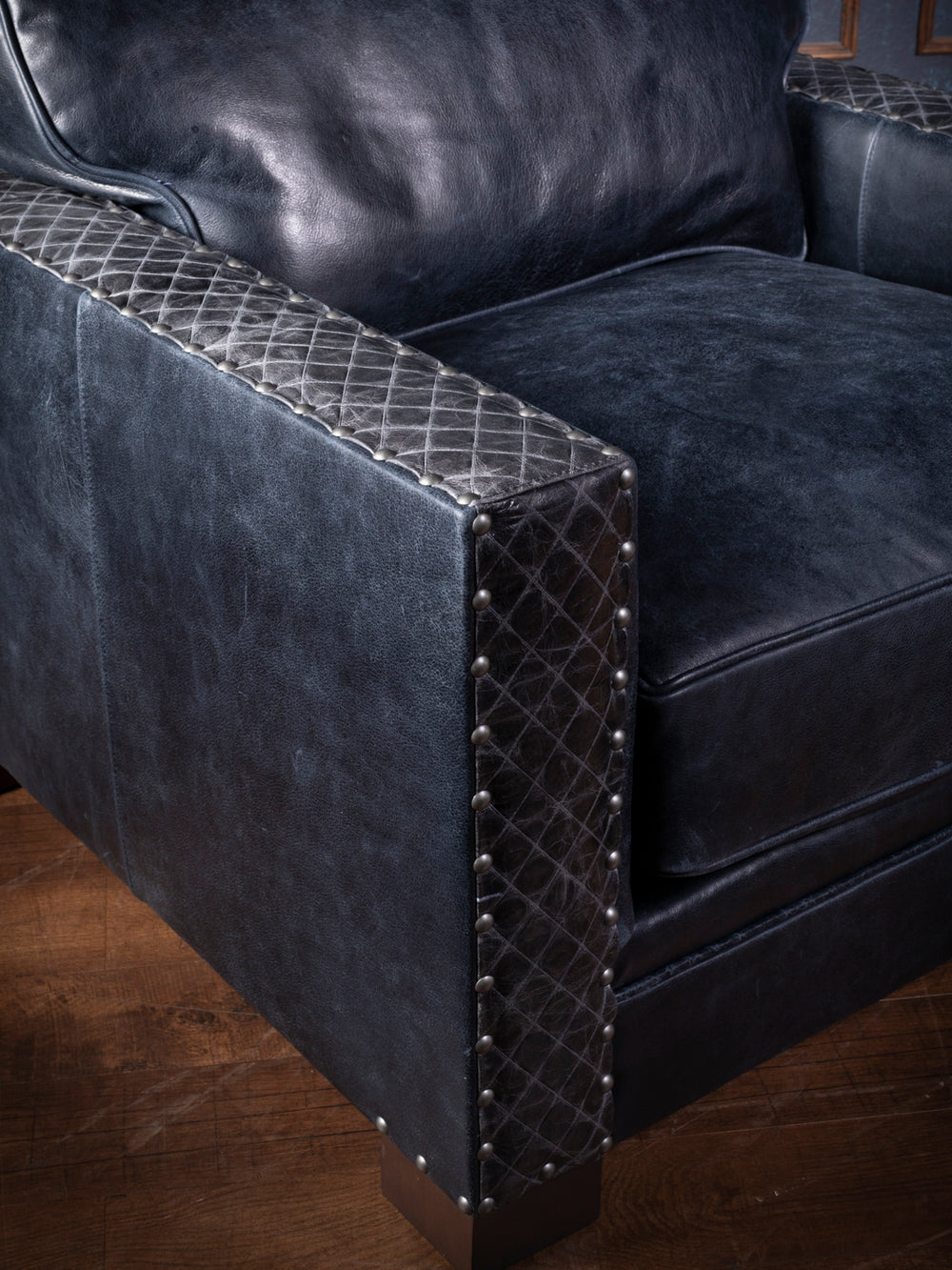 Side view of a plush blue leather armchair with decorative studs - Side perspective of a plush blue leather armchair, showcasing its soft texture and decorative studs along the arms, set in a stylish interior.