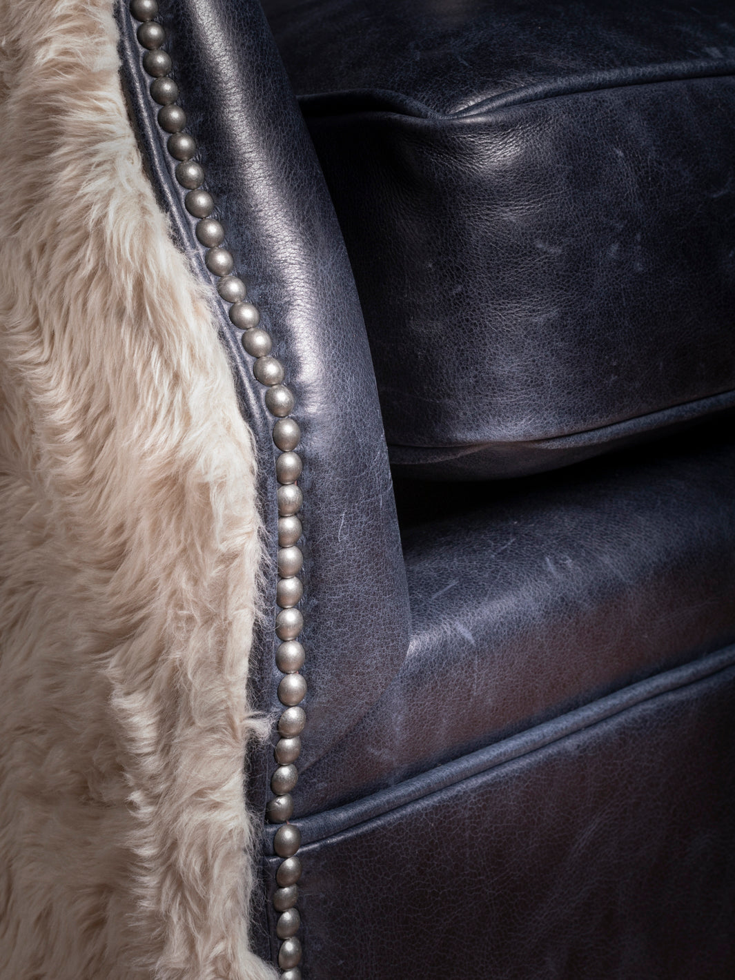 Close-up of Nailhead Trim Detailing on Cowboys Blue Leather Swivel Chair with Shearling Sides - High-quality Craftsmanship in Western-inspired Furniture Design.