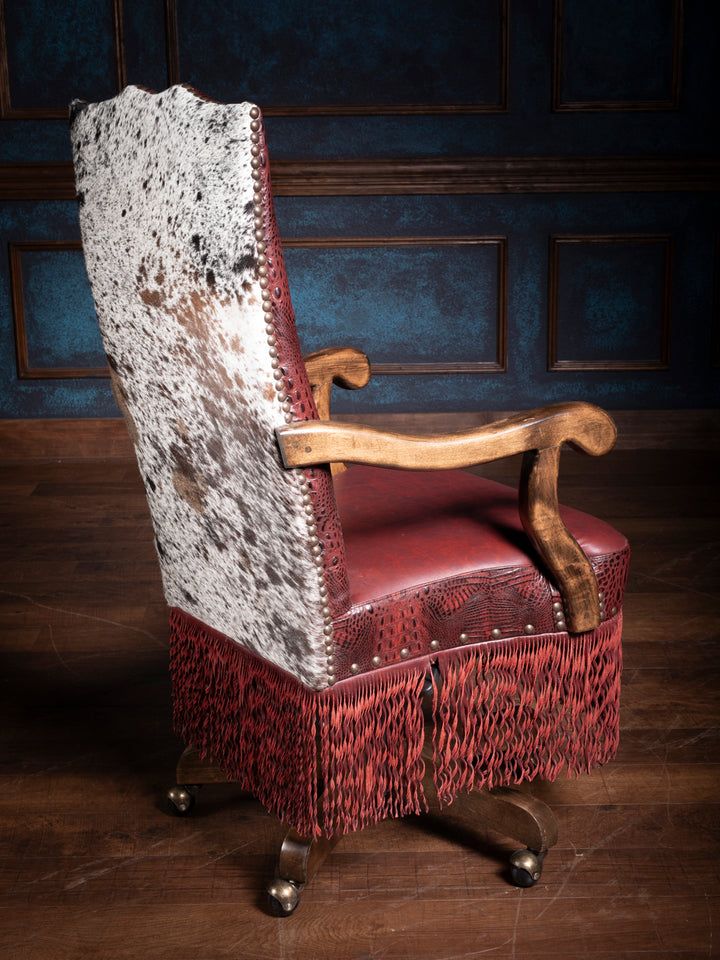 Rear view of a luxurious crimson leather desk chair with red leather fringe, highlighting the speckled black and white hair on hide.