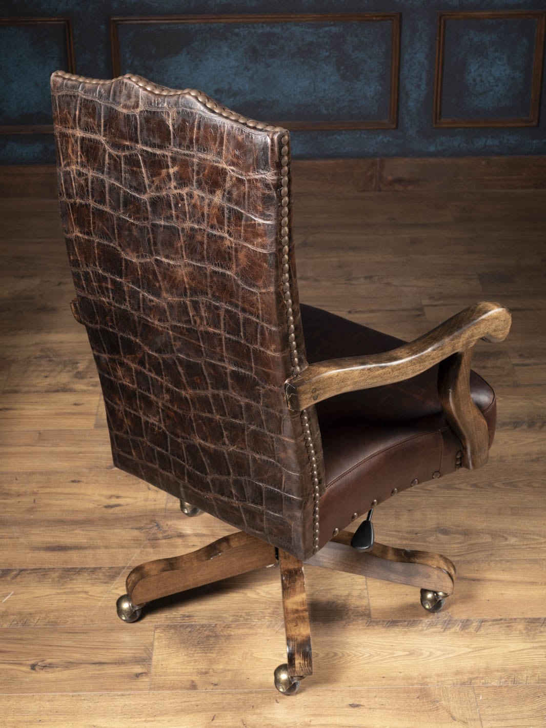 Three quarter rear view of the jumbo crocodile embossed leather high back and solid wood caster base on a Western executive desk chair.