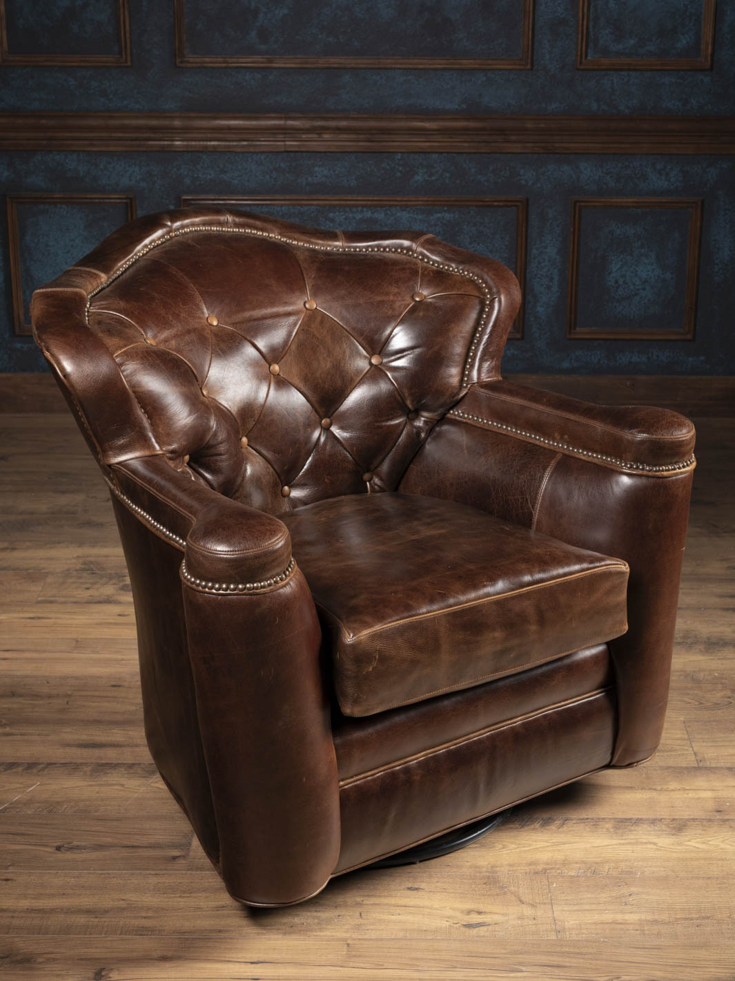 Side angle of the Dark Rum leather swivel chair showing sculpted armrests and hidden 360-degree swivel base.