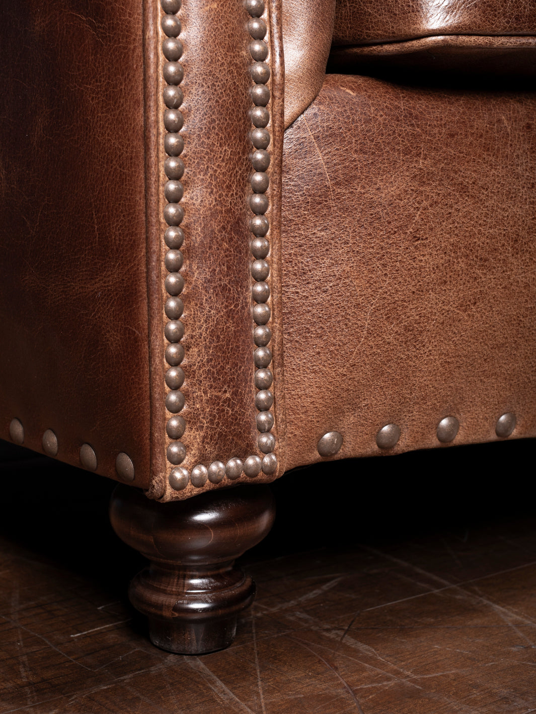 Dark Rum Rolled Arm Leather Sofa in brown full-grain leather with brass nailhead trim in a close-up view.