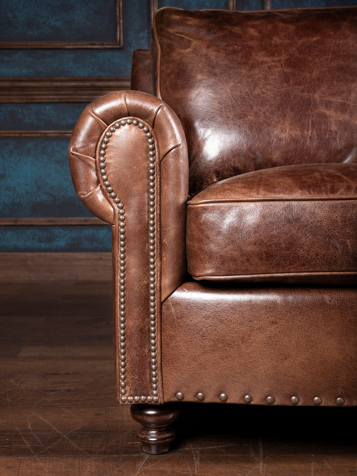 Dark Rum Rolled Arm Leather Sofa in brown leather with brass nailhead trim in a rustic inspired room.