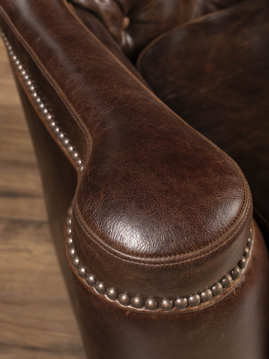 Nailhead trim detail along the curve of the Dark Rum tufted leather swivel chair