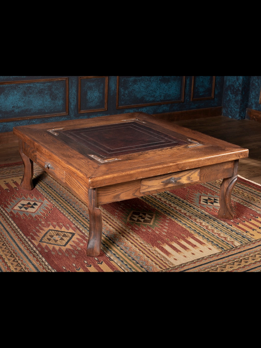 Nevada Cocktail Table with rustic distressed brown wood featuring leather inlay top and side storage drawer shown in a spacious living room setting.
