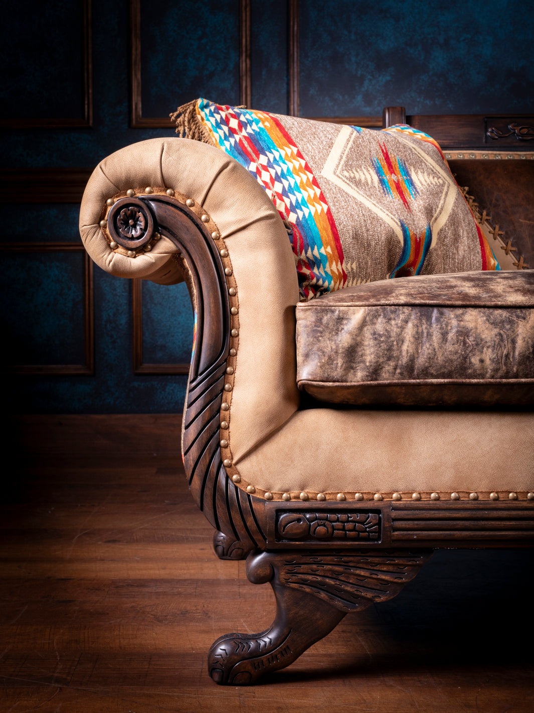 Duncan Phyfe steer leather sofa featuring hand-carved wood detailing and a nailhead trim design in a close up view.