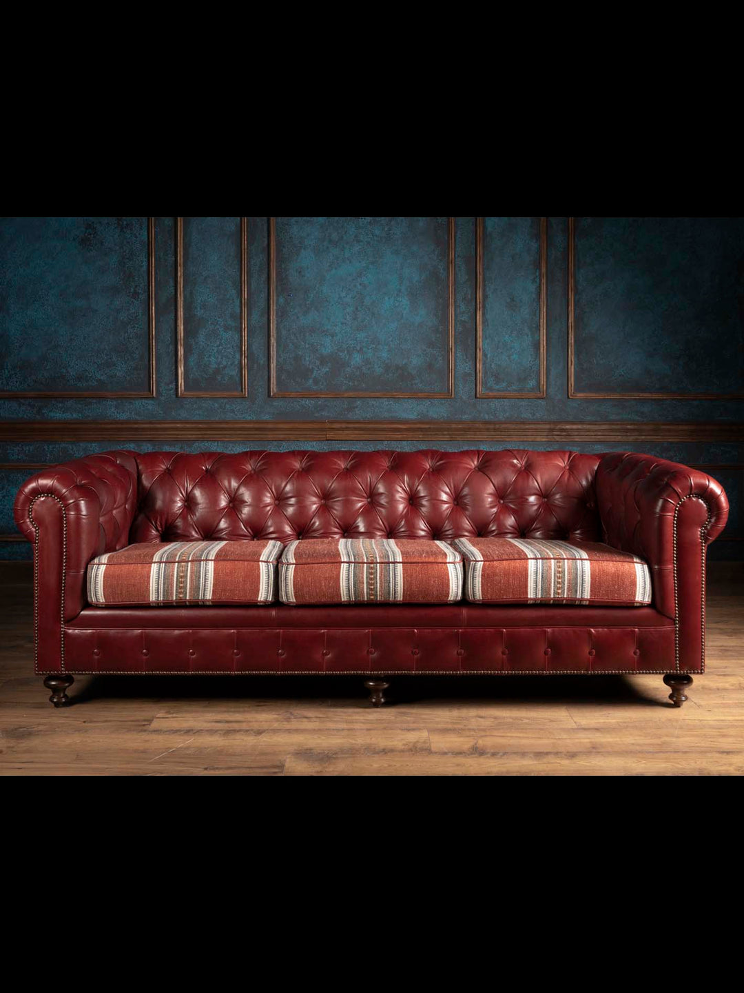 The West Texas Estate Chesterfield Sofa in hand tufted oxblood leather featuring custom Southwestern fabric wrapped cushions as seen on Landman.