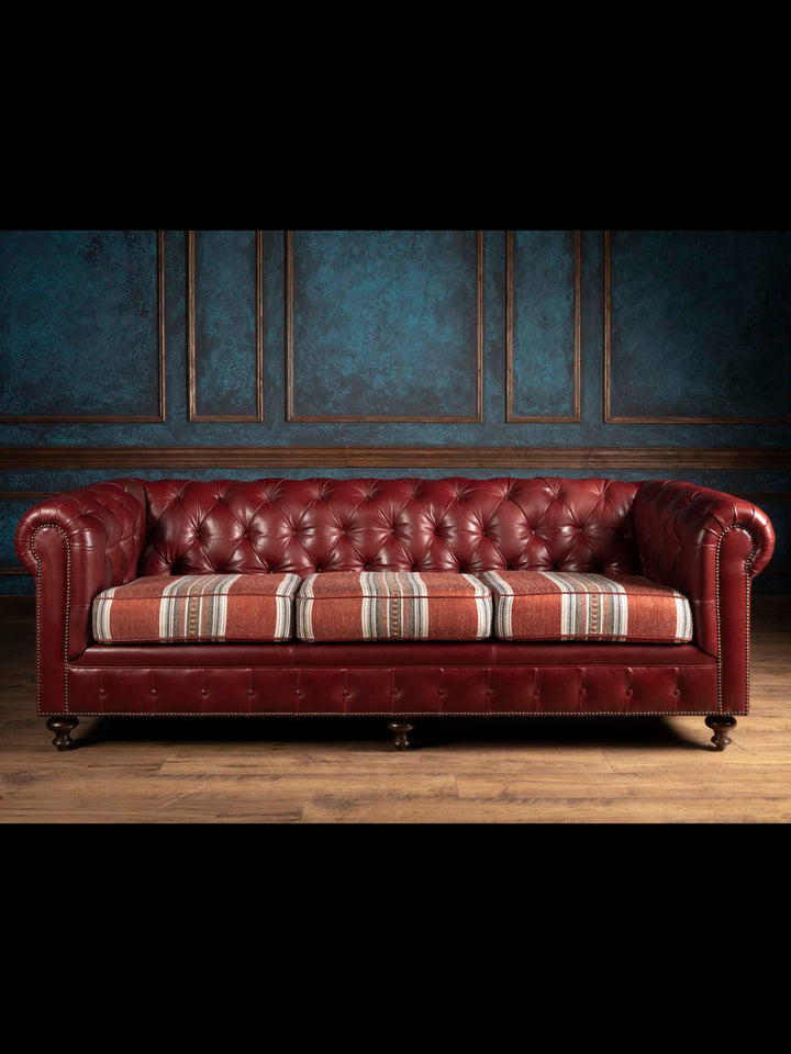 The West Texas Estate Chesterfield Sofa in hand tufted oxblood leather featuring custom Southwestern fabric wrapped cushions as seen on Landman.