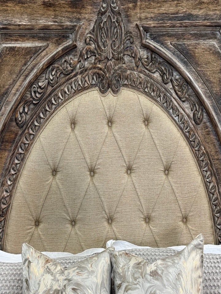 Decorative headboard with tufted upholstered panel and ornate wooden frame.