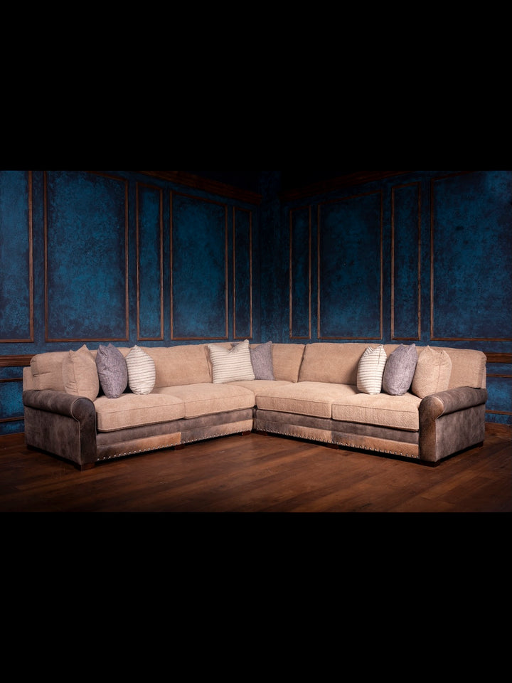 Beige sectional sofa with patterned cushions against a dark blue wall.