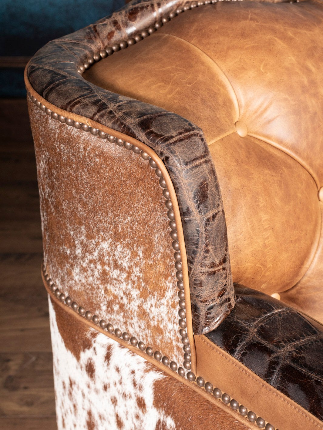 Golden Range Leather Sofa with a embossed crocodile trim and brass nailhead detailing in a close up view. 
