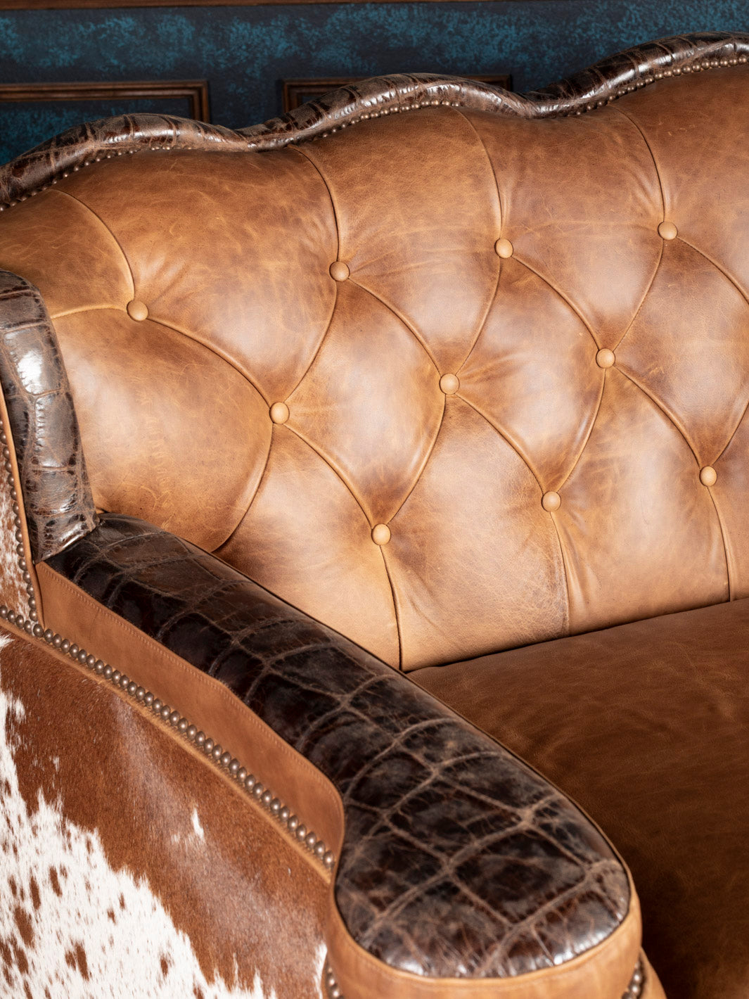 Golden Range Leather Sofa in a chestnut brown leather with deep tufted inside back detailing and crocodile accents in a close up view. 