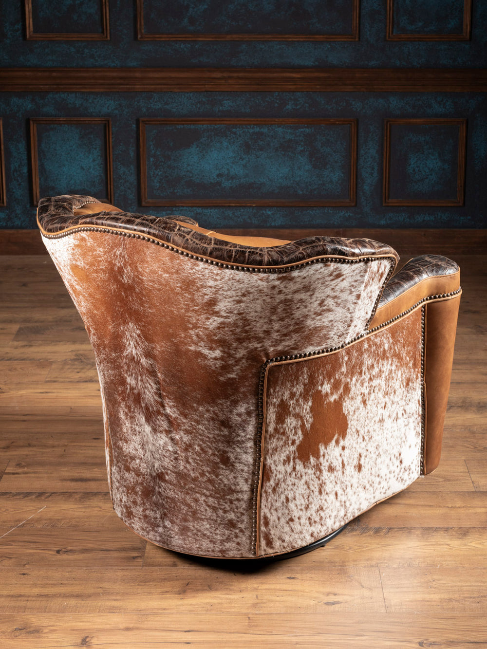 Golden Range Swivel Chair featuring cowhide outside back with brass nailhead trim in a rustic space.