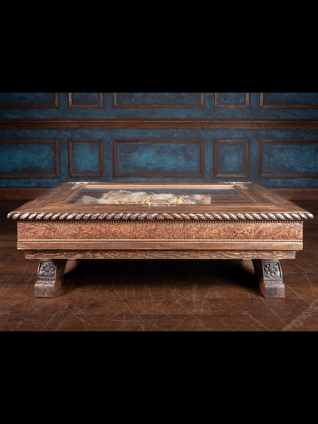 Saddle Ridge Shadow Box Coffee Table made of solid wood with brown finish featuring hand-carved western details and embossed floral leather trim in rustic living room setting.