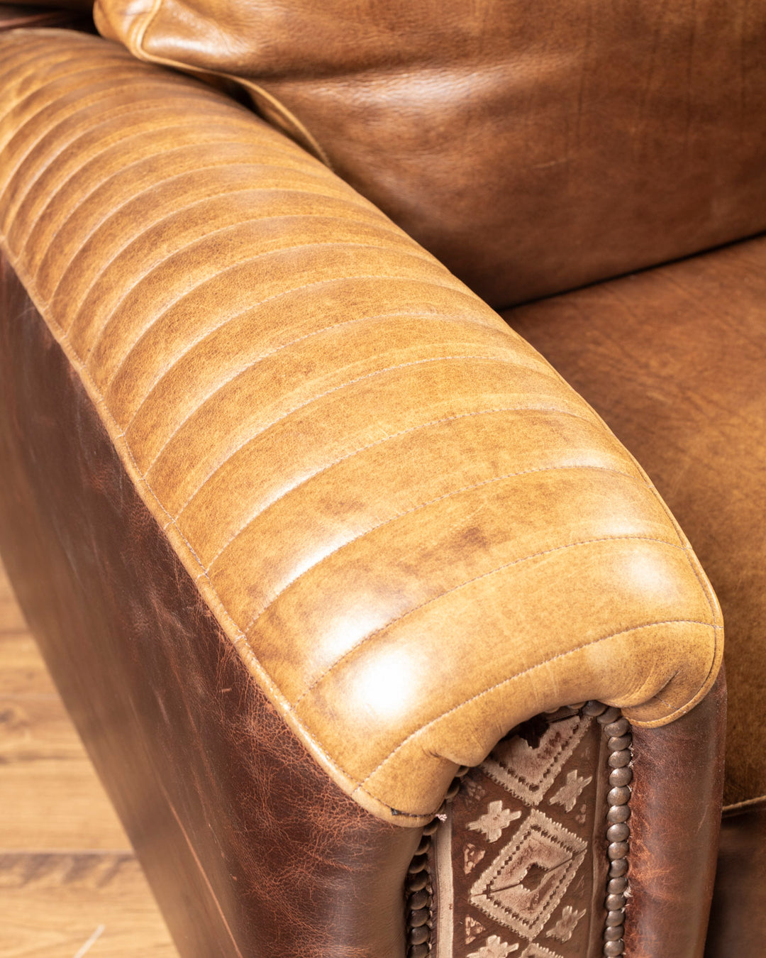 Detailed close-up view of the artisan hand-pleated leather treatment running along the rolled armrest of the Dutton chair.
