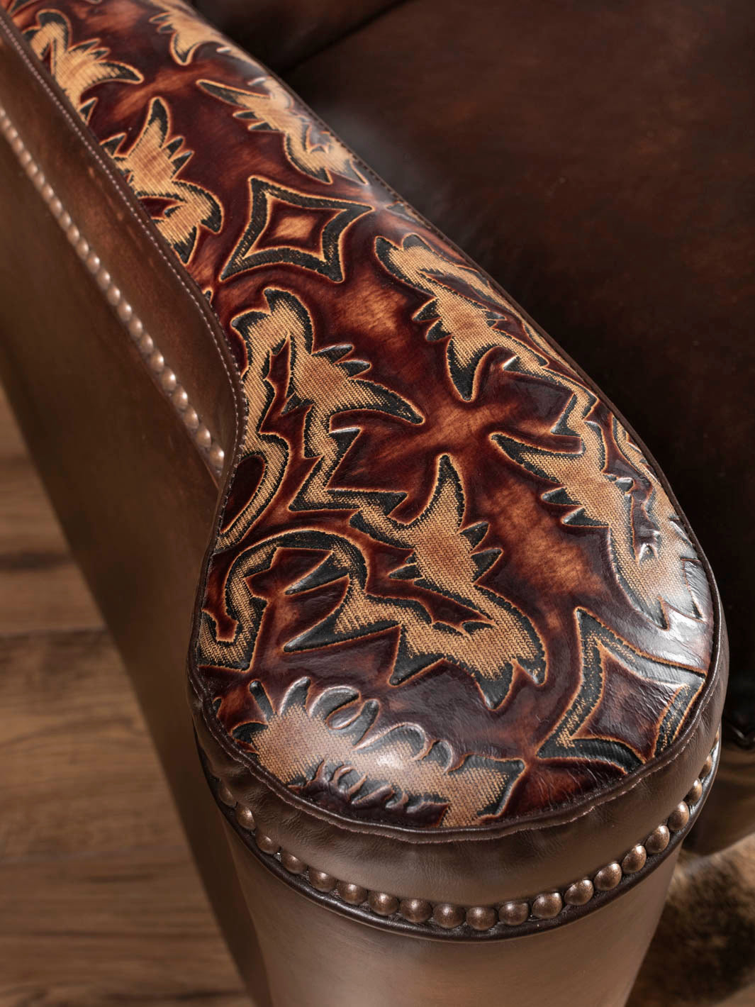 Hand-applied nailhead trim detail on the paneled arm of the leather recliner