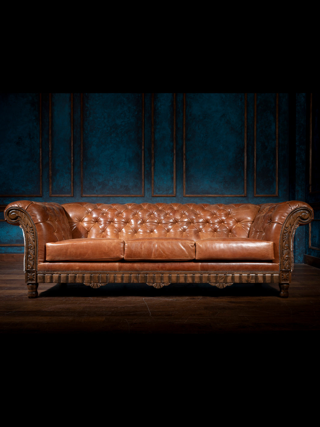 Brown leather sofa against a dark blue wall