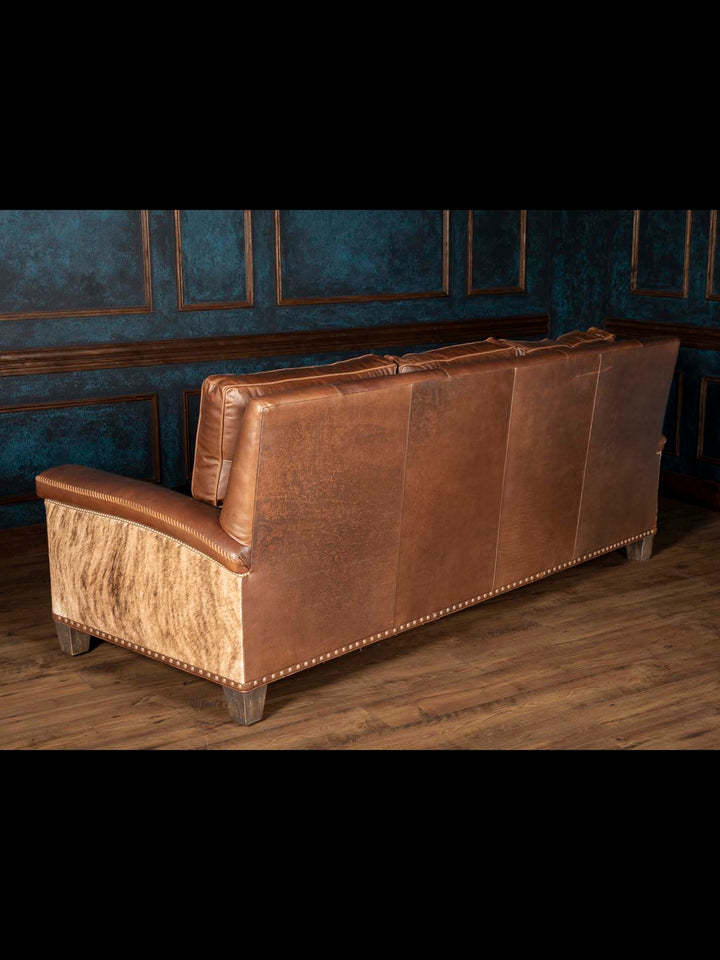 Rear view of Heritage Whipstitch sofa with brown leather back panels, a natural cowhide side and nailhead trim.