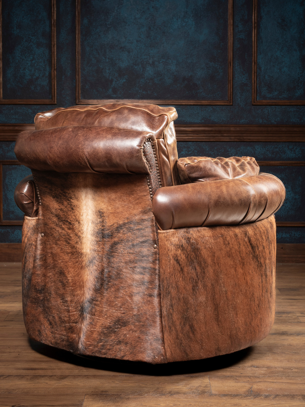 Hideout Leather Snug Swivel Recliner with brindle cowhide outside back and brown leather upholstery in a rustic living space.