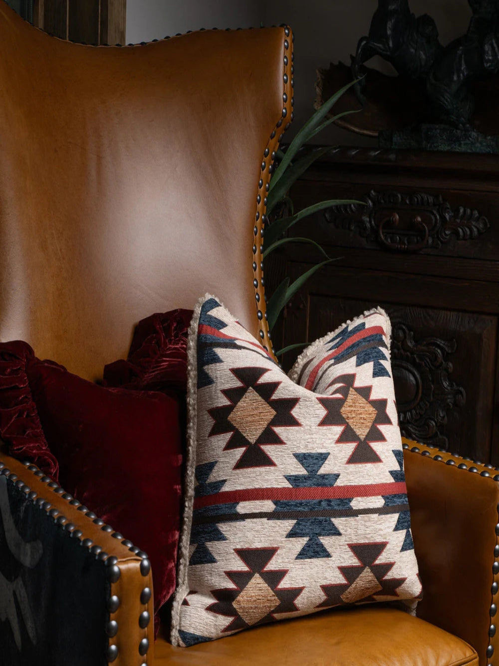 Patterned pillow on a brown leather armchair with decorative elements.