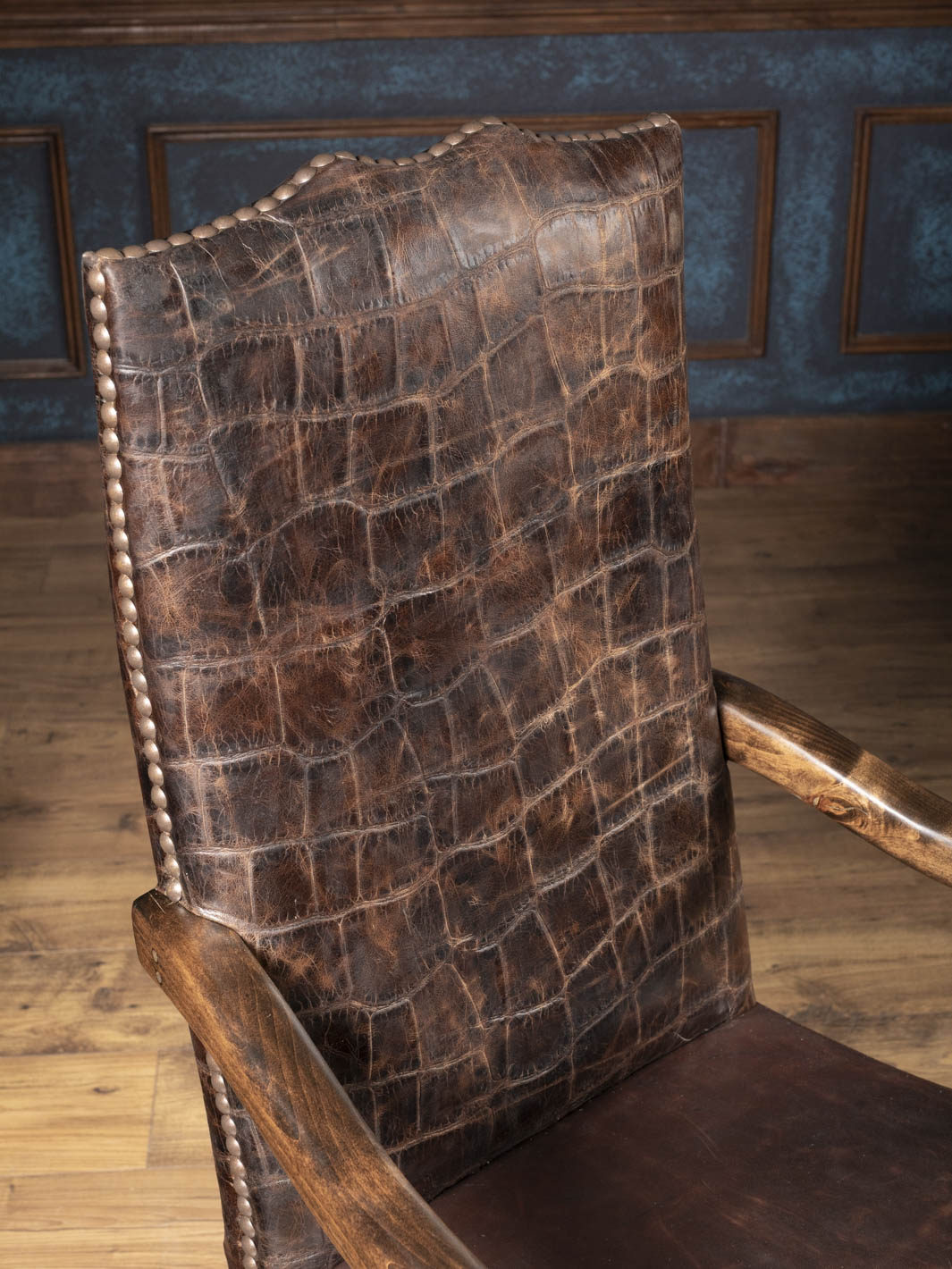 Close up view of the jumbo crocodile embossed leather high back with hand-driven nailhead trim on a Western executive chair.