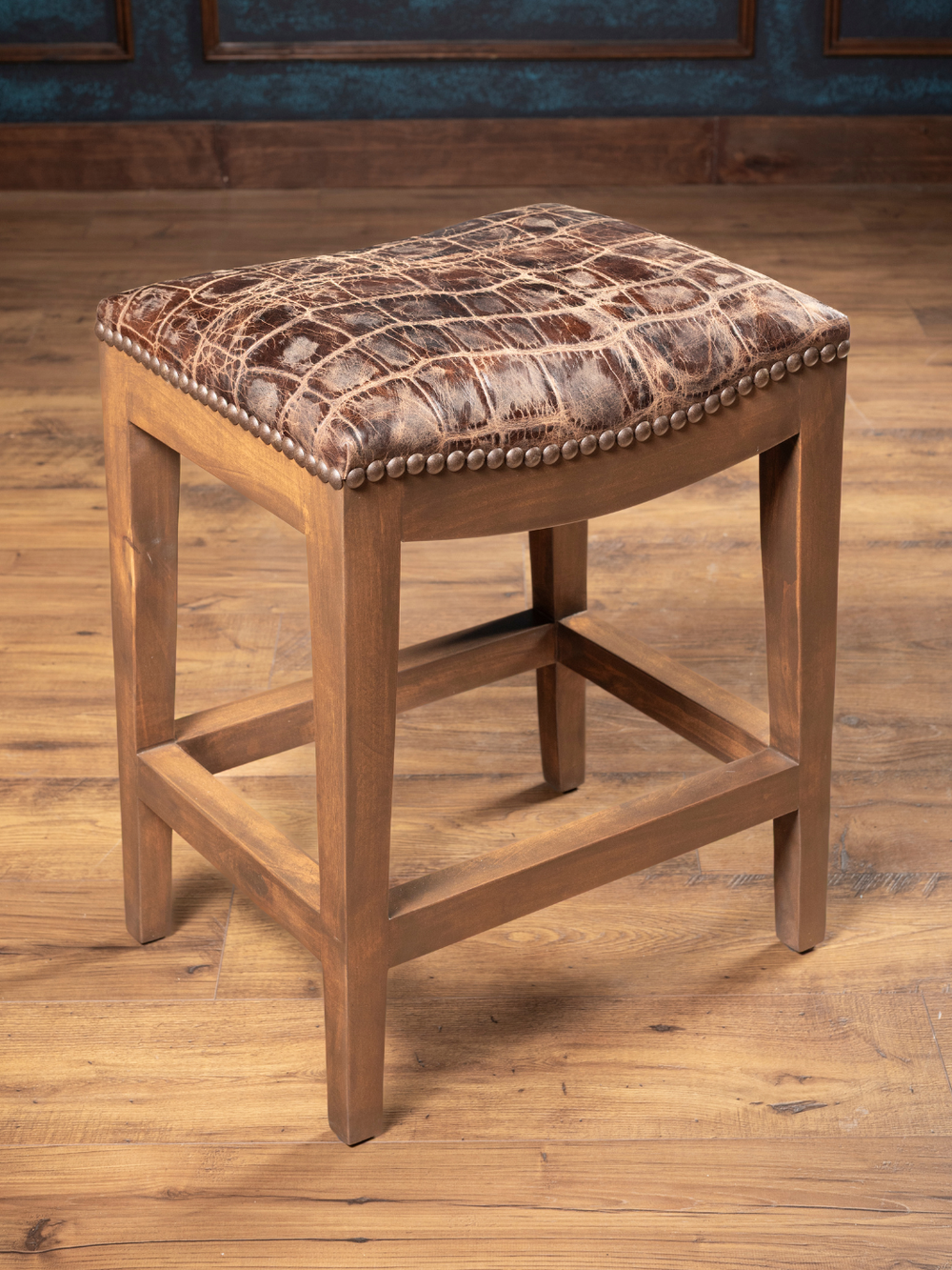 Jumbo Crocodile Leather Saddle Stool crafted from solid hard wood and rustic leather accents in a kitchen space.