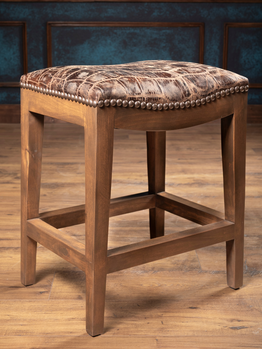 Jumbo Crocodile Leather Saddle Stool with a embossed crocodile leather seat and solid hardwood in a kitchen space. 