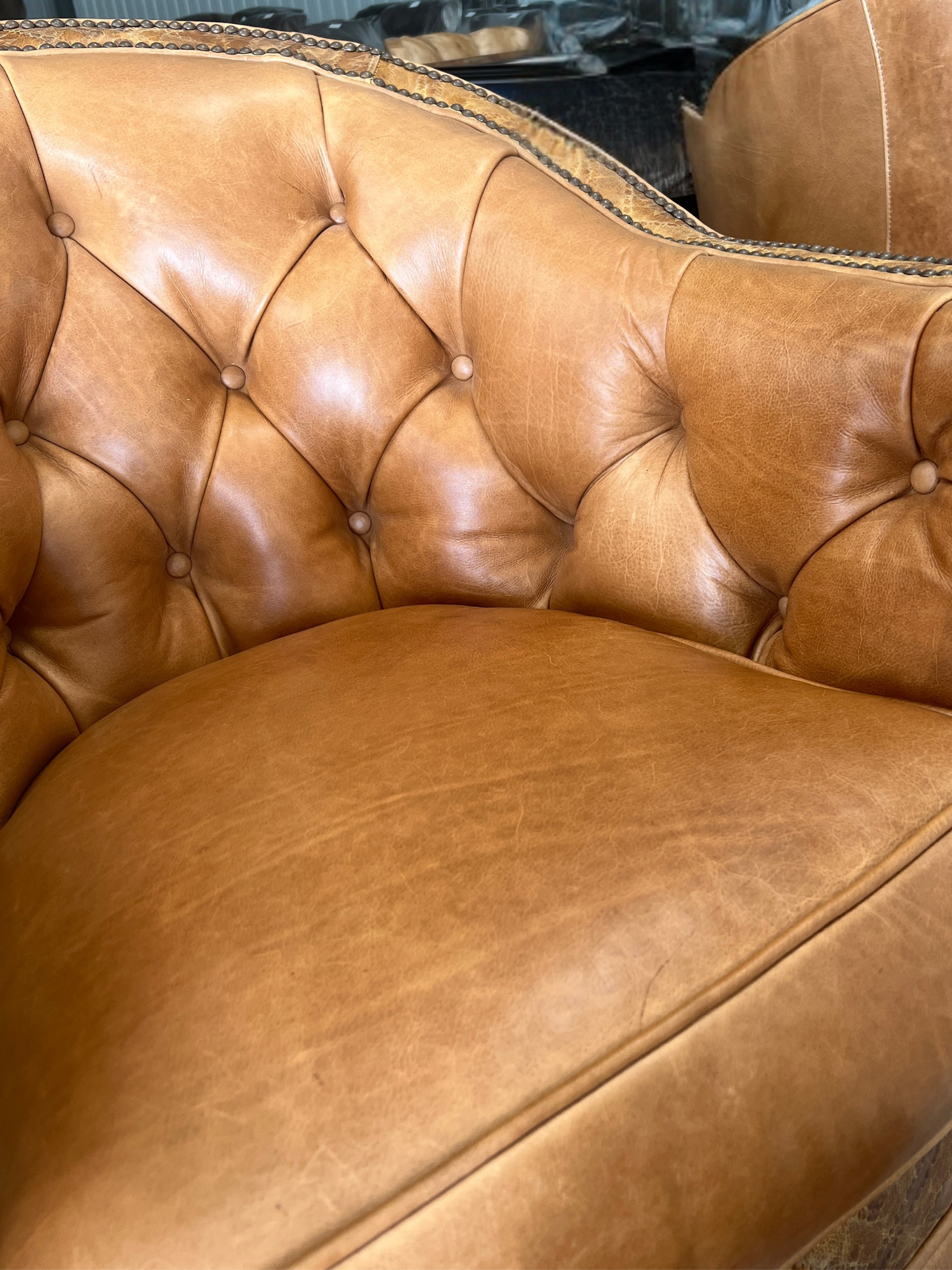 The same tan tufted leather chair seat after repair, with an even unmarked surface