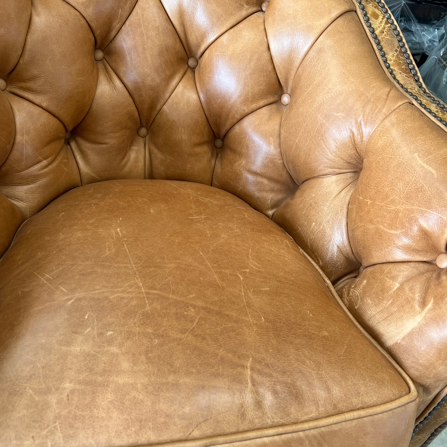 Tan tufted leather chair seat with visible pale scratching across the cushion before repair