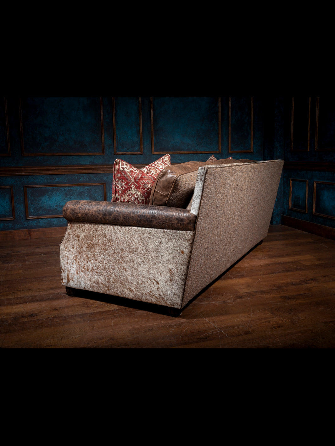 Luxurious Leather and Fabric Sofa with cowhide panels and fabric outside back in moody western space.